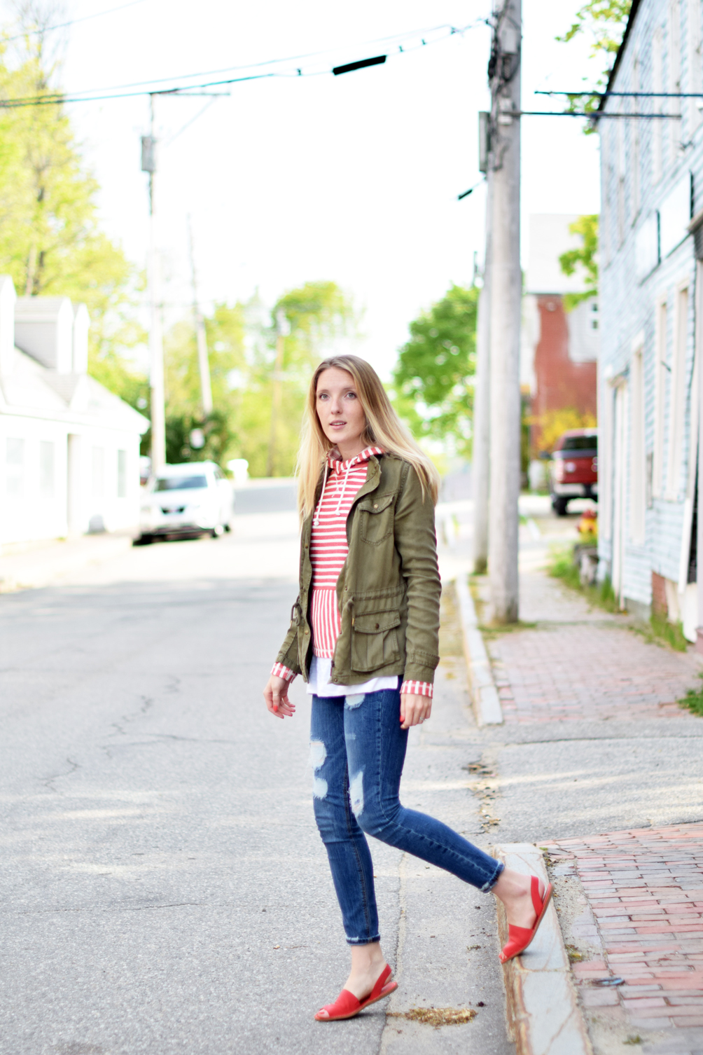 spring style, nautical striped hoodie with destructed denim, red slide sandals, and an army green jacket, leslie musser of one brass fox