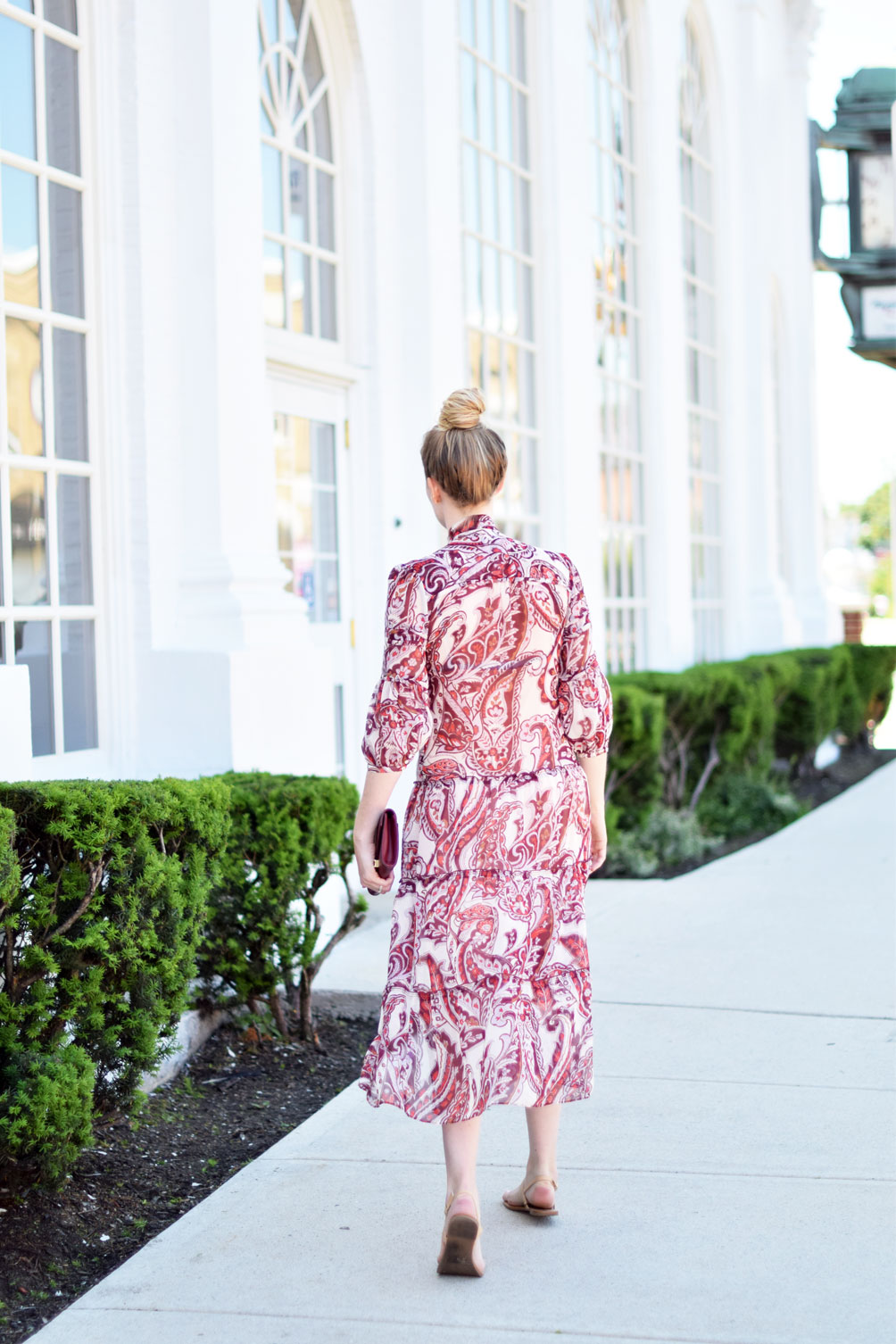 tie neck peasant midi dress with an oxblood clutch and simply top knot on Leslie Musser of one brass fox