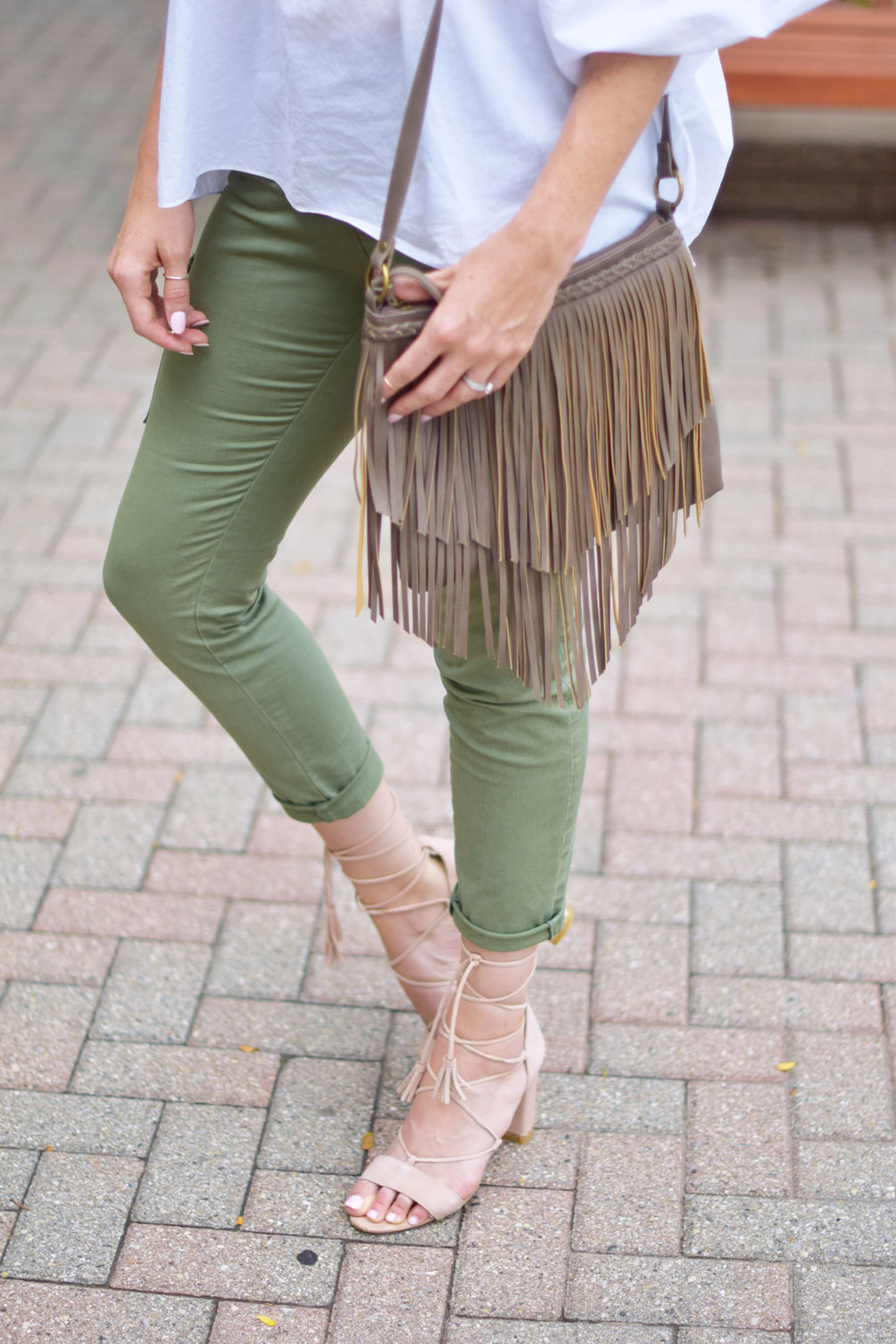 Leslie Musser wears utility cargo pants with lace up sandals and a fringe crossbody bag on one brass fox