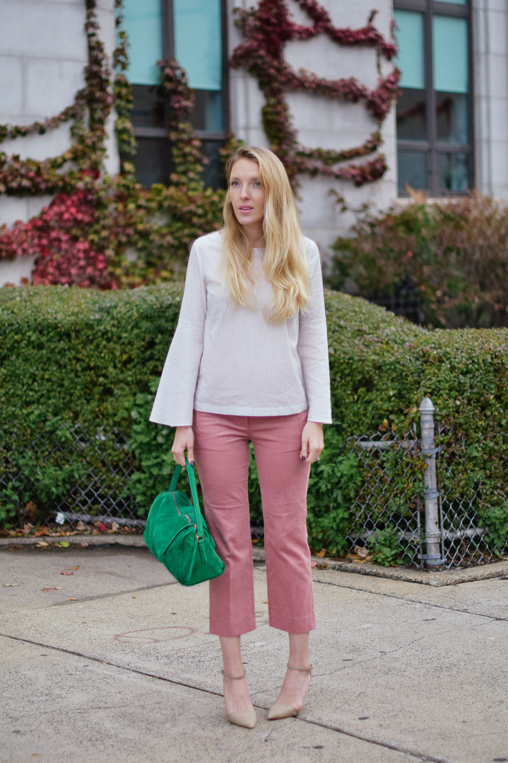 Leslie Musser wears cropped blush corduroys with a striped bell sleeve top and emerald tote on one brass fox