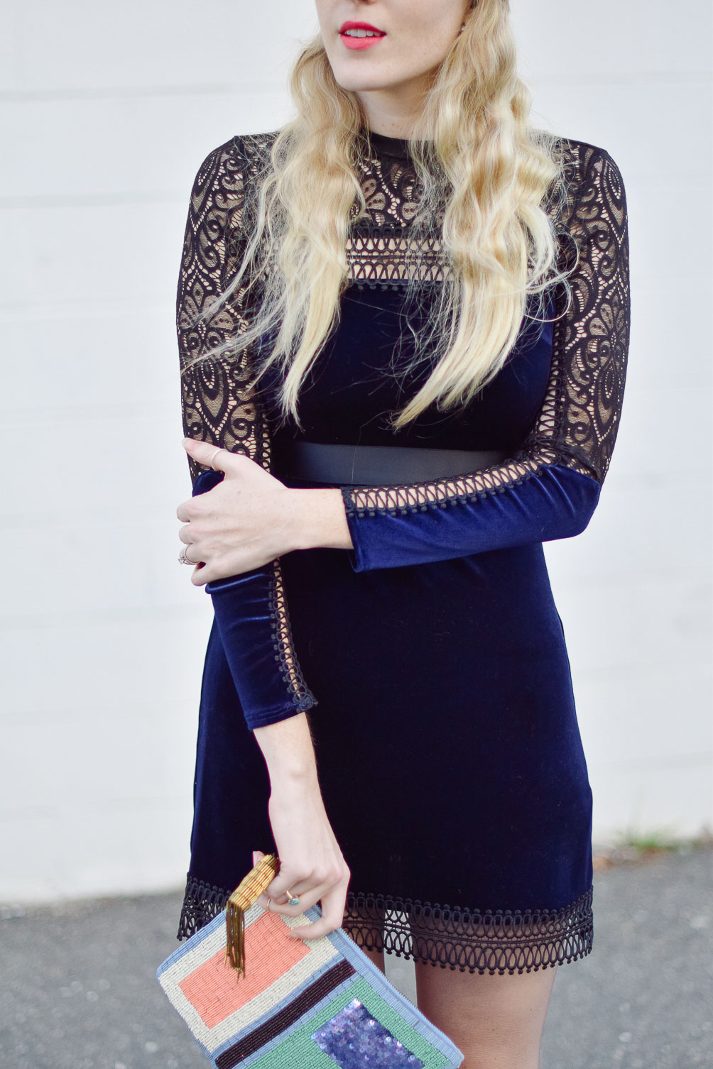 wearing a blue velvet lace mini dress with beaded clutch and patent leather heels