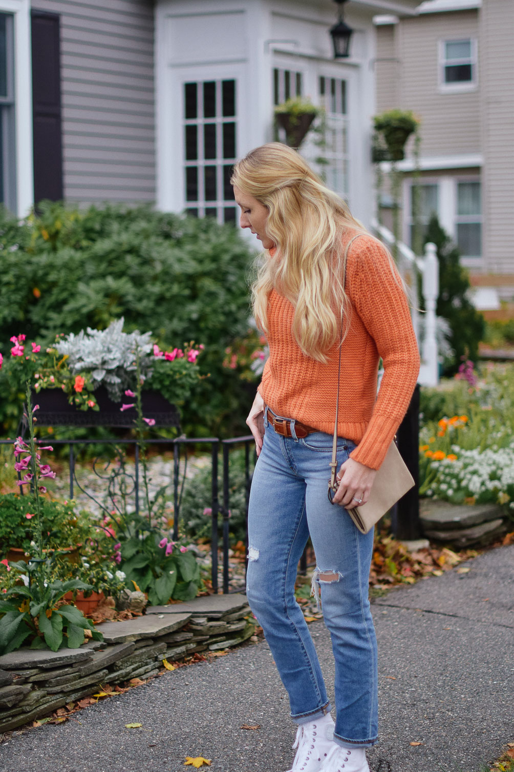 Leslie Musser dressing for sweater weather in an orange turtleneck and real straight jeans with high top sneakers on one brass fox