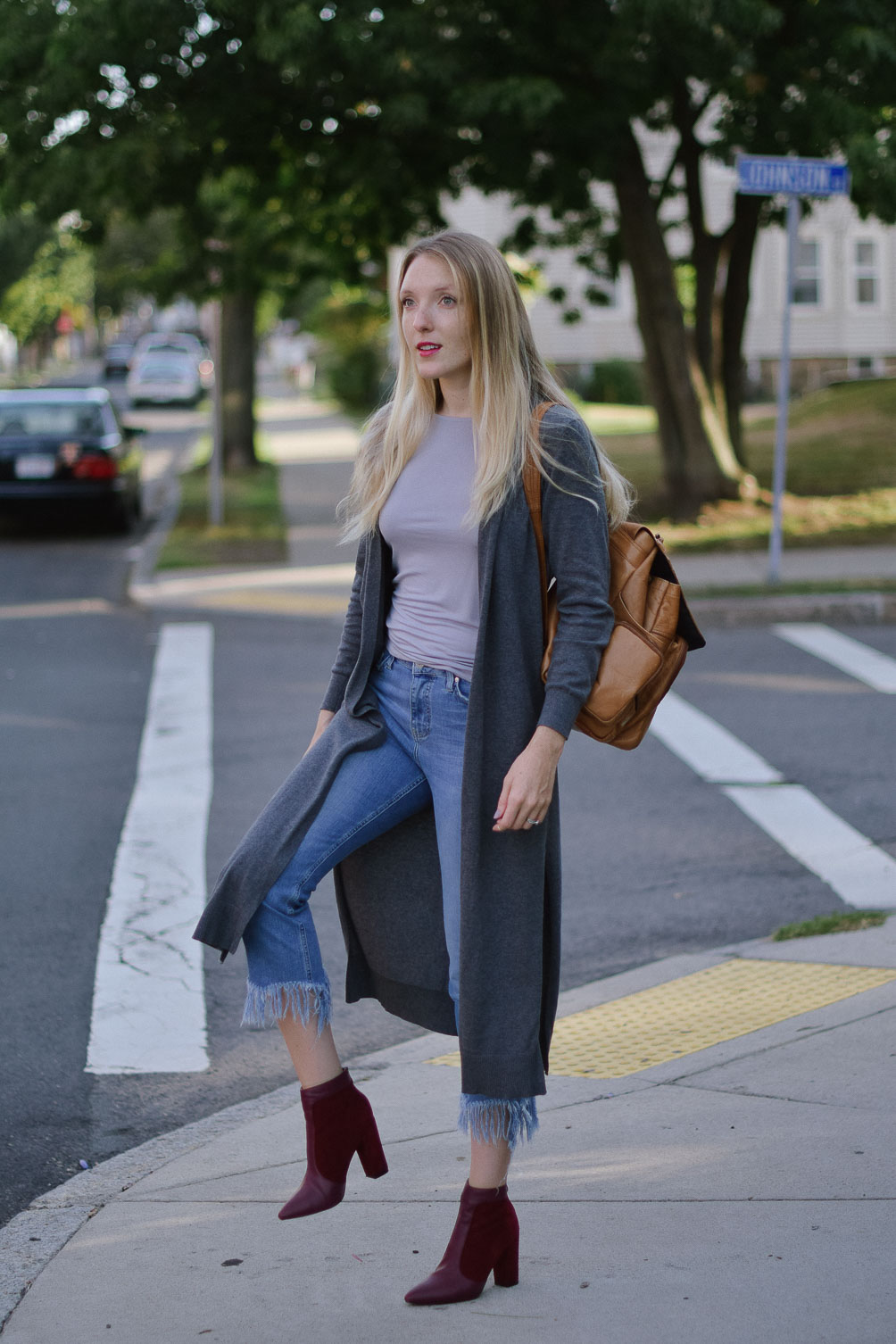 Leslie Musser wearing fringe hem jeans with a duster sweater and suede oxblood boots on one brass fox