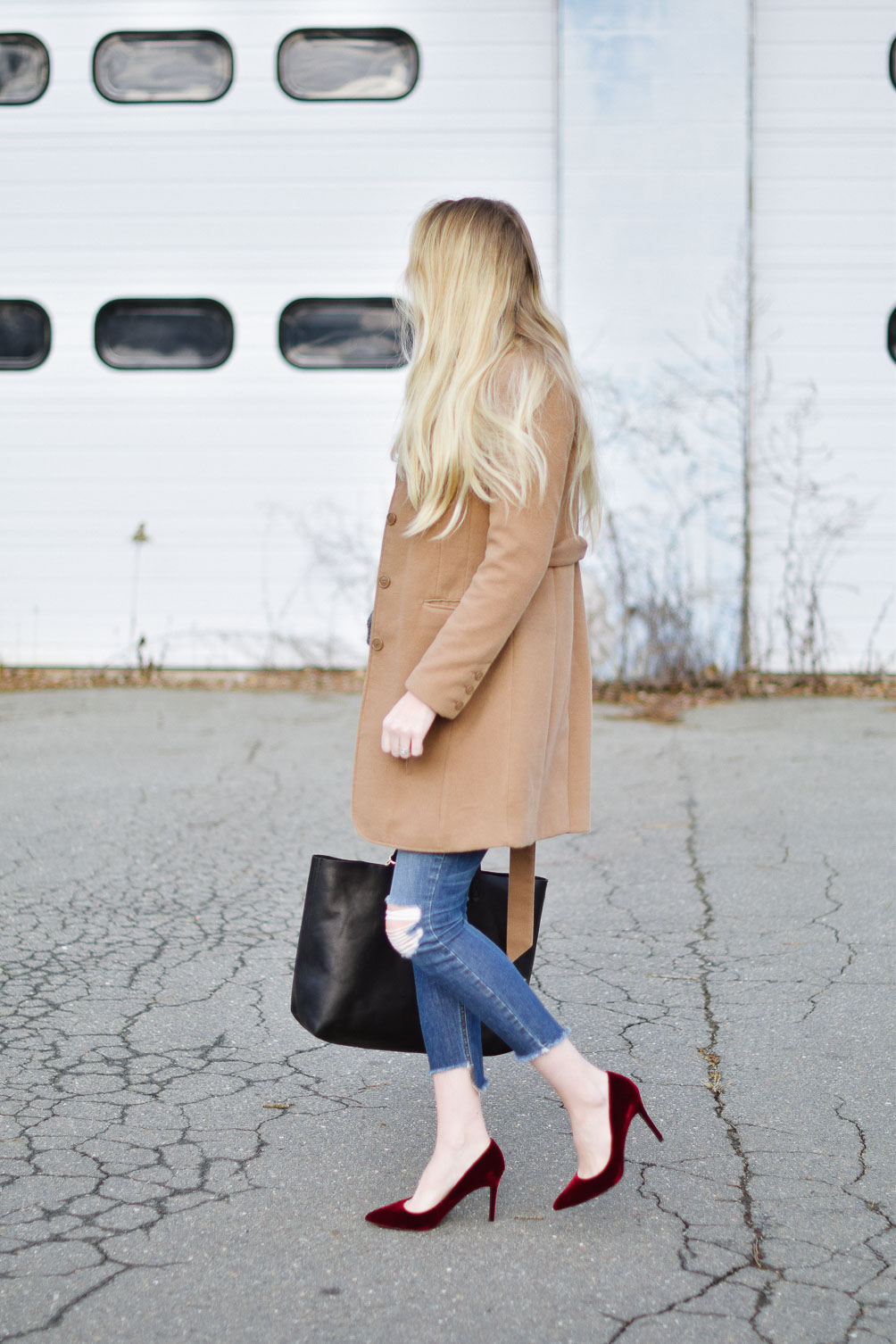 styling a layered winter outfit with this camel coat, chunky sweater, distressed denim, and velvet pumps
