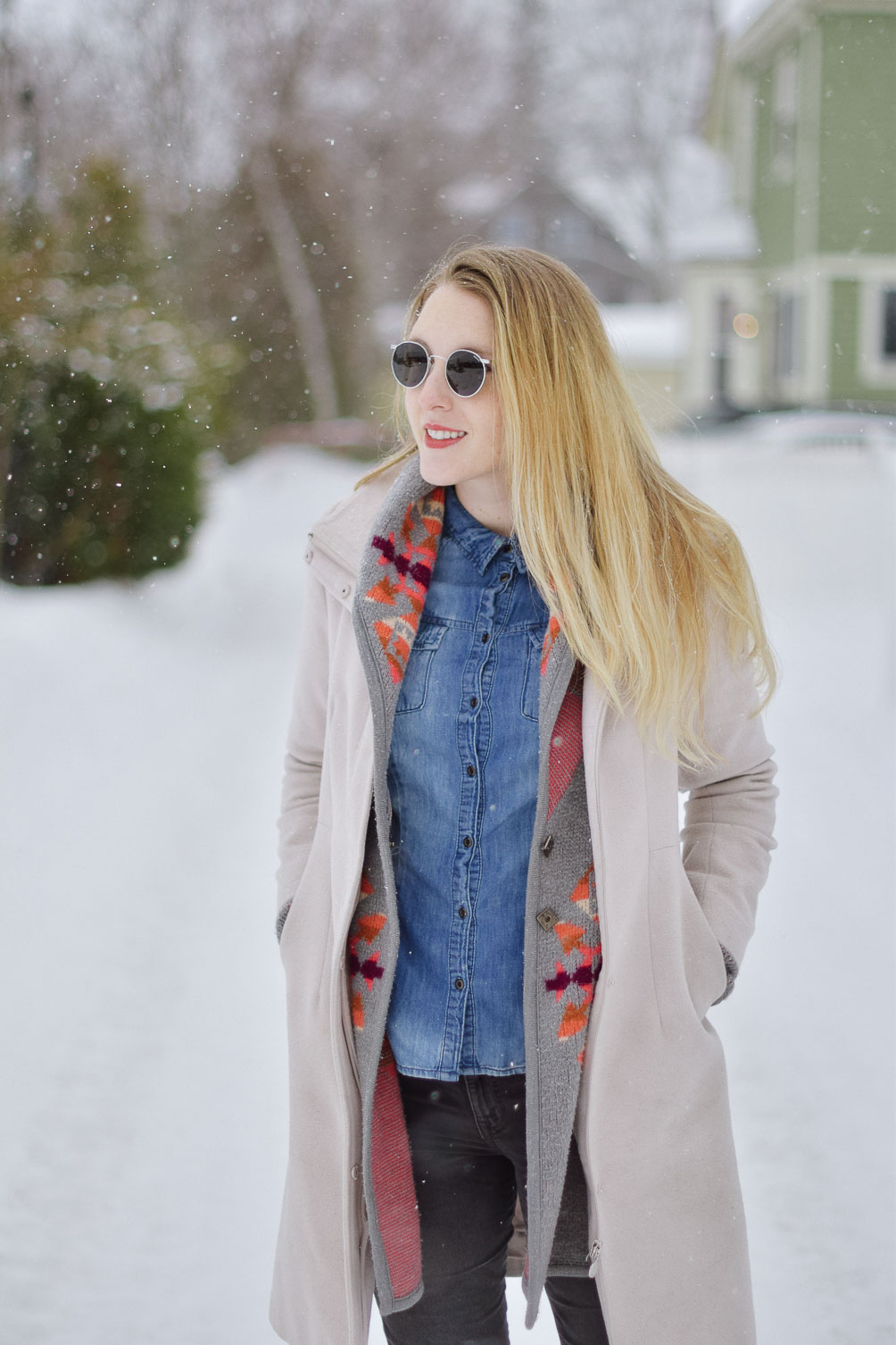styling this cozy winter look with an aztec print sweater, chambray shirt, gray skinny jeans, and round sunglasses