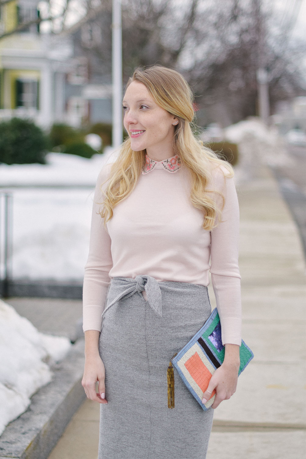 styling an embroidered collar sweater with tie waist skirt and beaded clutch