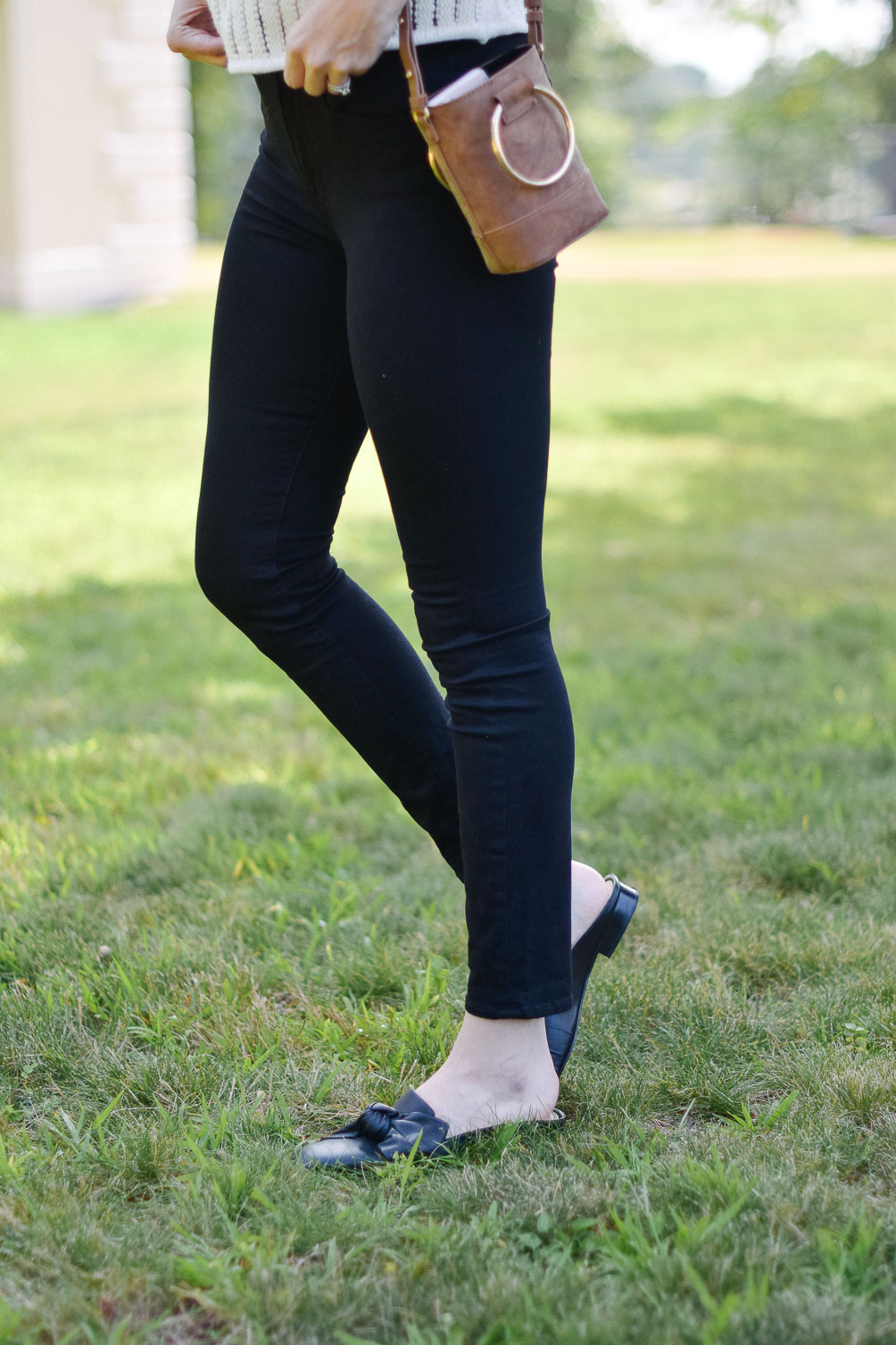 Leslie Musser styling a short sleeve sweater with black skinny jeans and leather mules for transitional fall style