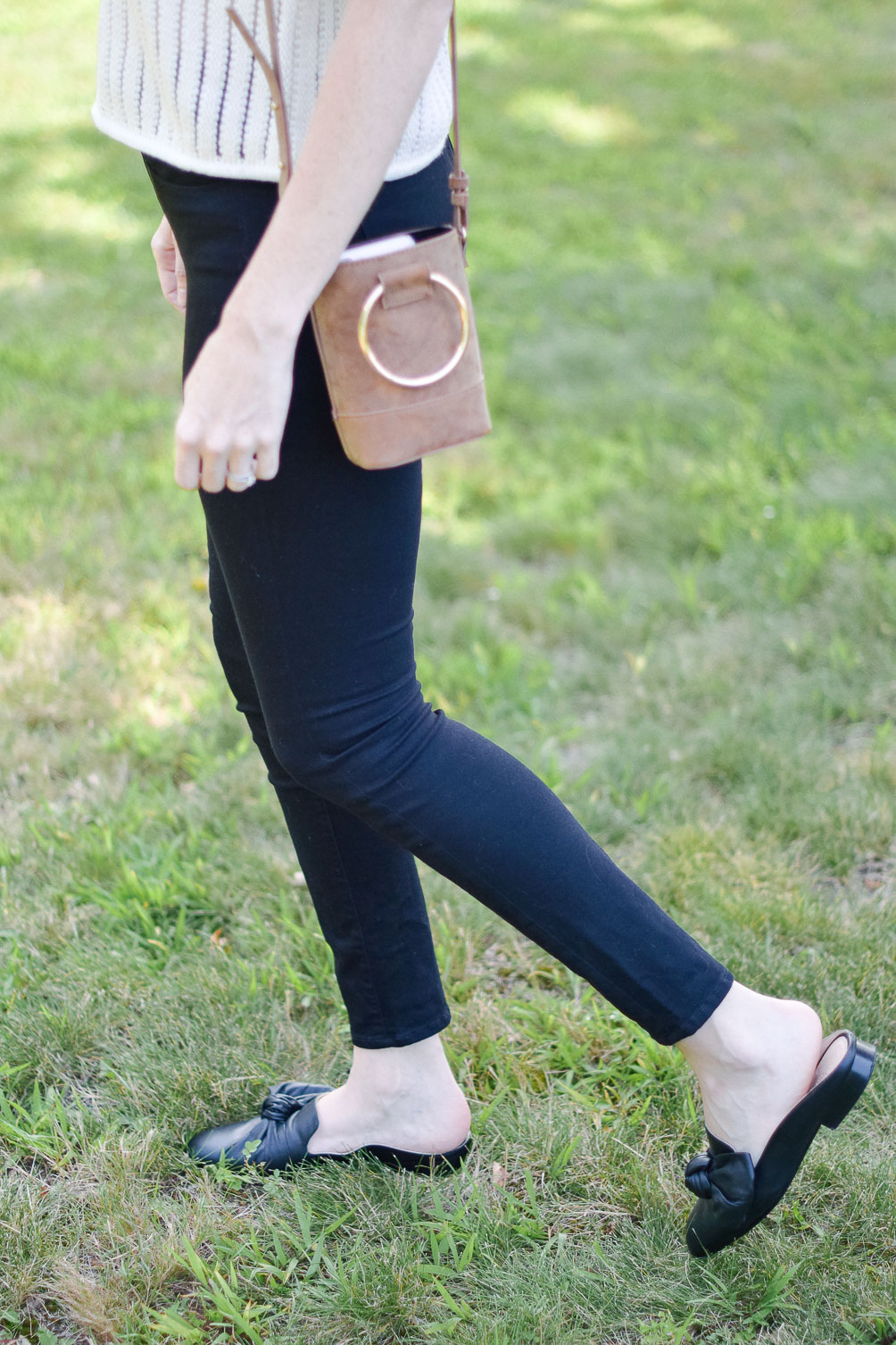 Leslie Musser styling a short sleeve sweater with black skinny jeans and leather mules for transitional fall style