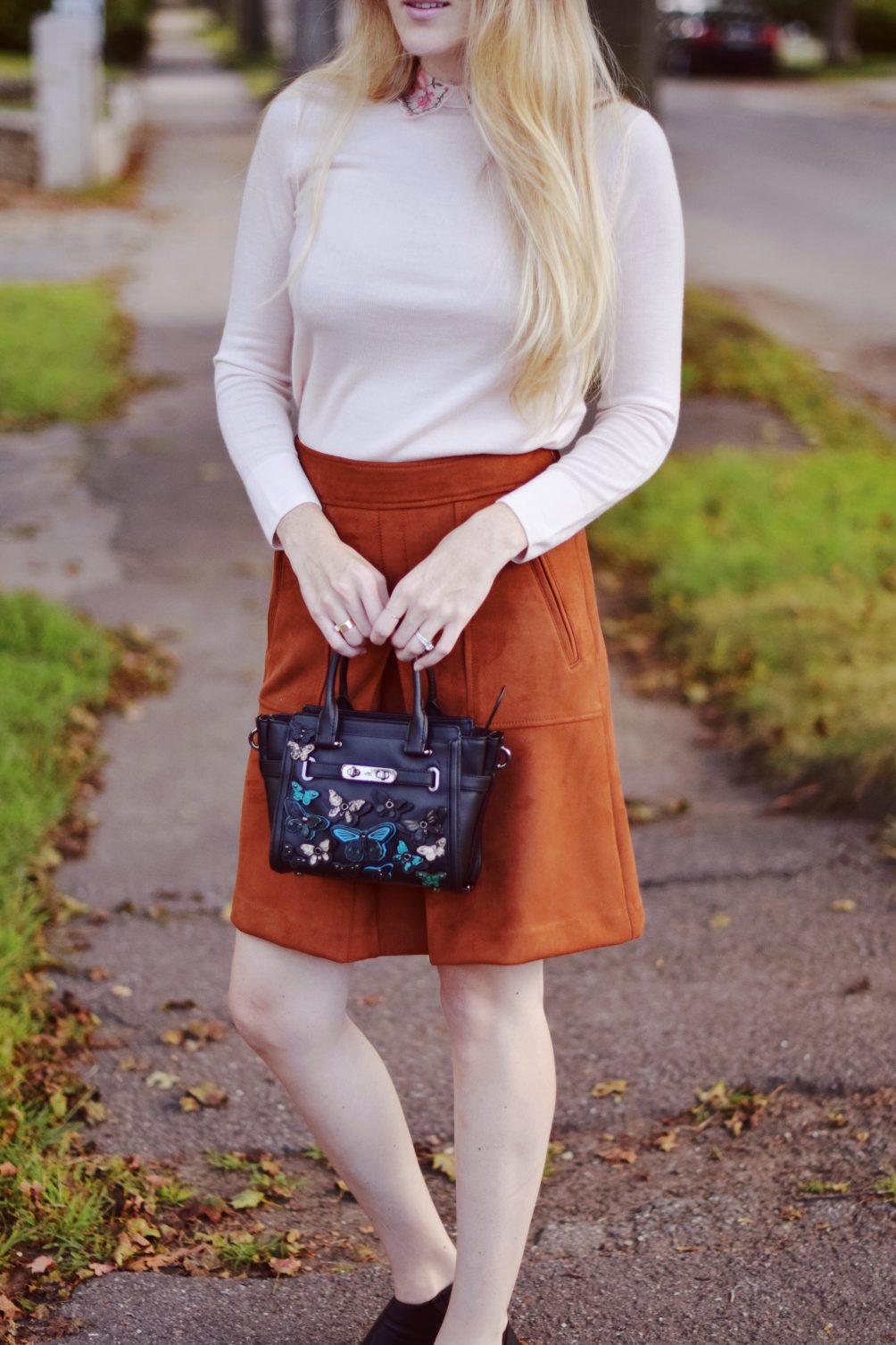suede rust skirt on leslie musser with Club Monaco pink embroidered sweater and Coach appliqué bag for fall style outfit