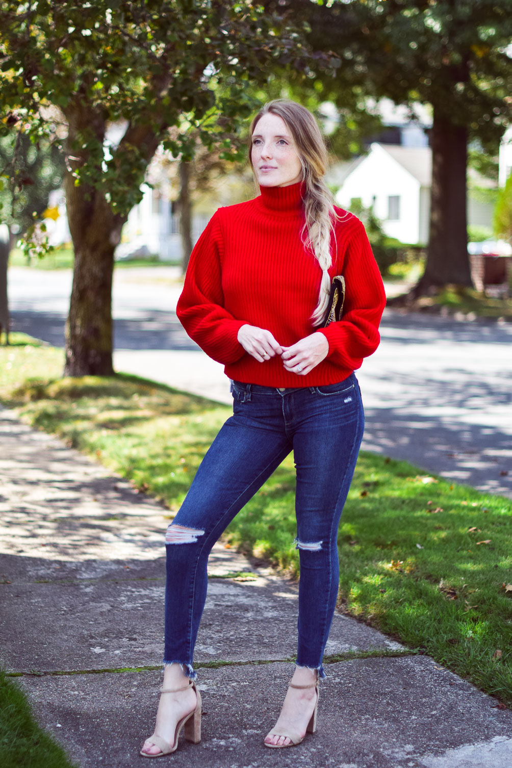 wearing a bright chunky red sweater with step hem jeans and block heel sandals