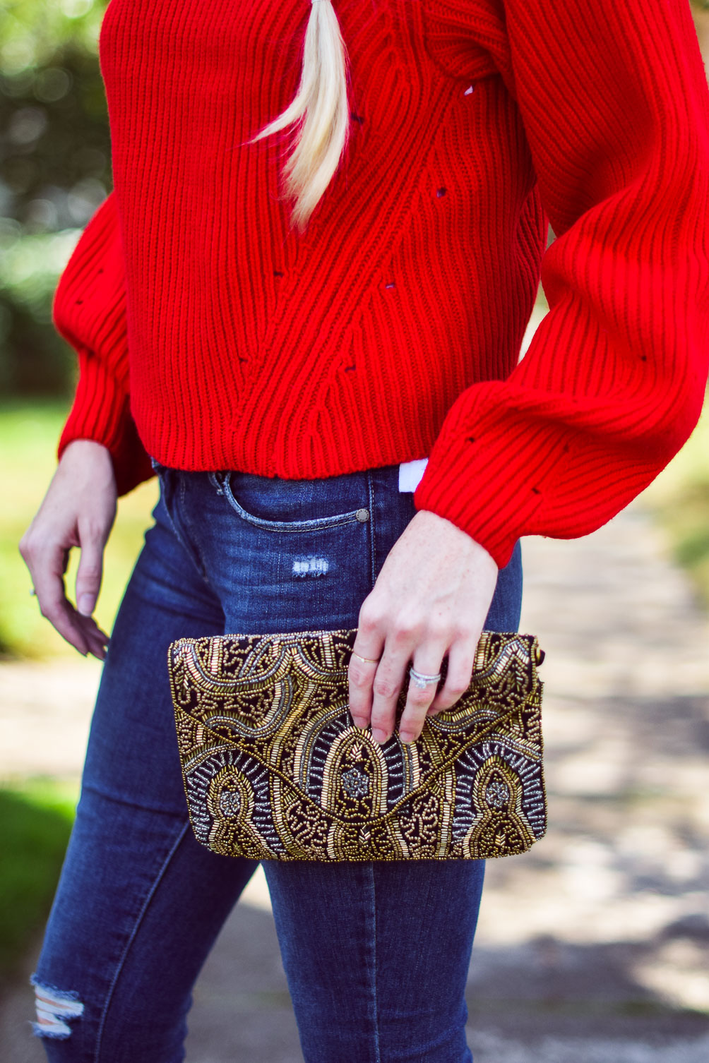 wearing a bright poppy red cashmere blend sweater with step hem jeans and block heel sandals