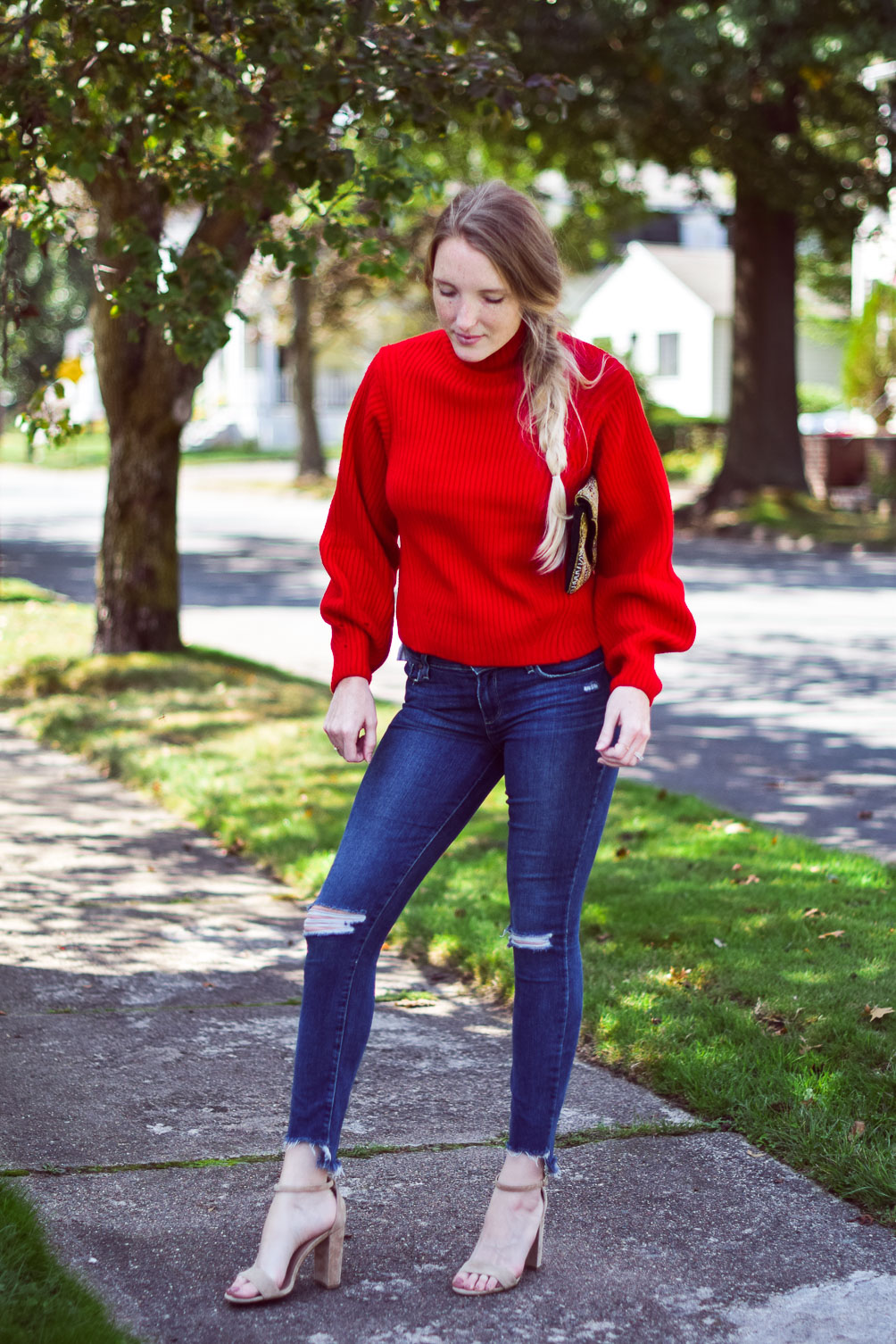 wearing a bright poppy red cashmere blend sweater with step hem jeans and block heel sandals