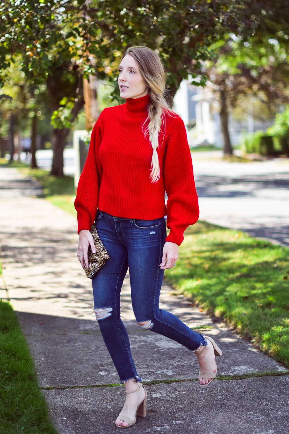 wearing a bright chunky red sweater with step hem jeans and block heel sandals
