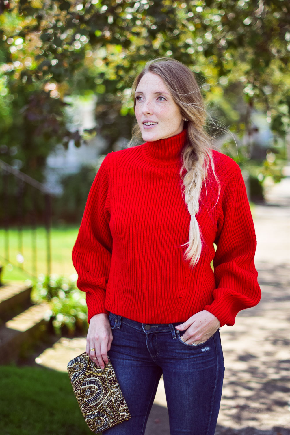wearing a bright poppy red cashmere blend sweater with step hem jeans and block heel sandals