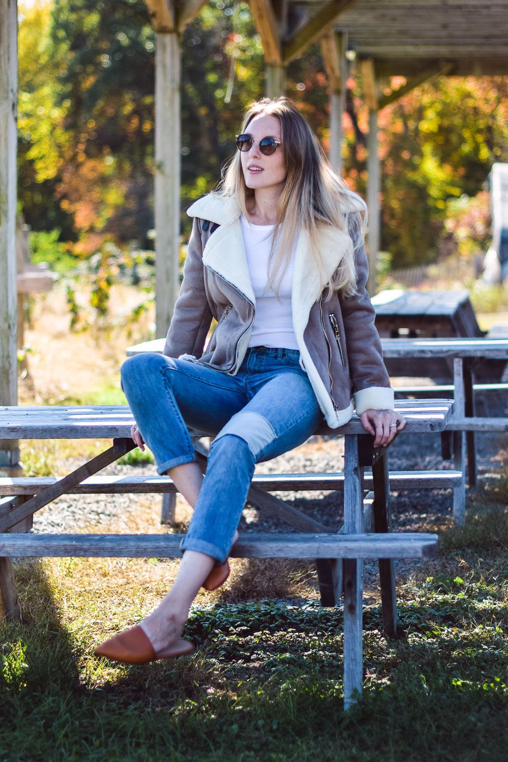 styling this faux suede moto jacket for fall and winter with a white henley, patched boyfriend jeans, and tan slides