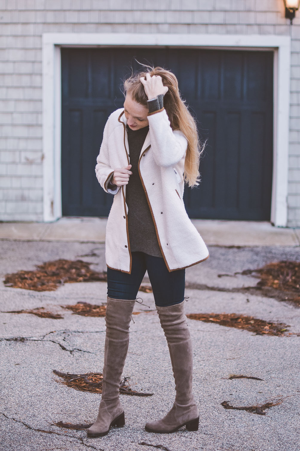 wearing a faux white sherpa jacket for styling neutrals with this cashmere sweater and over the knee Stuart Weitzman boots