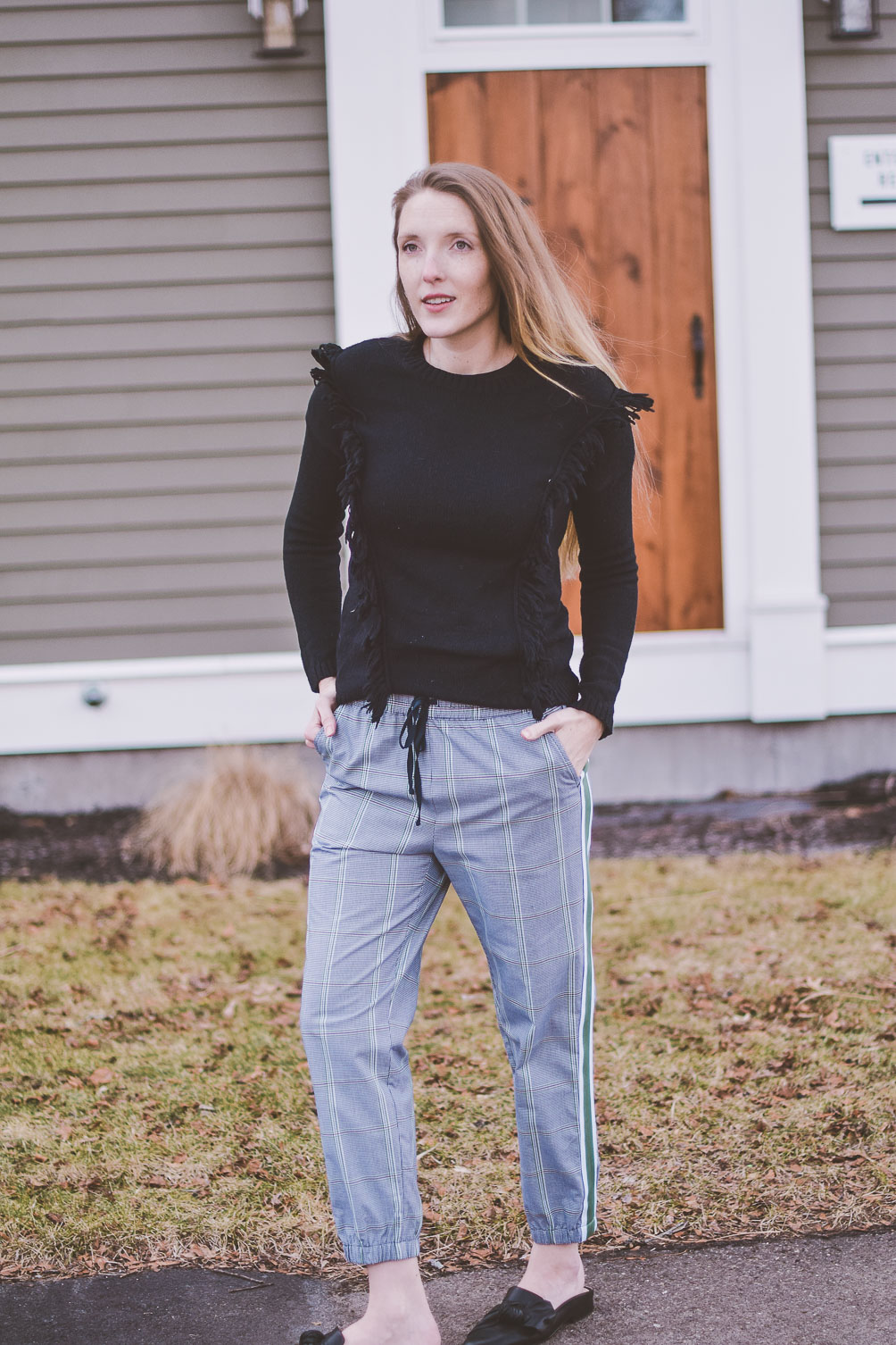 styling a modern checked track pant for everyday wear with black leather mules and a fringe sweater