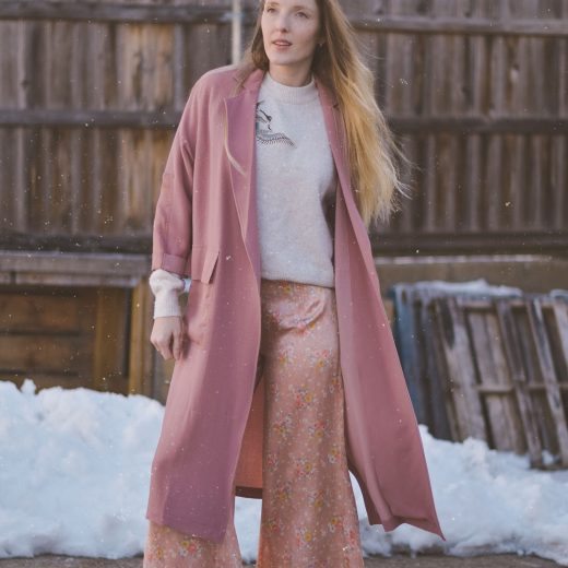 styling pastel pink for spring with a lightweight trench, appliqué sweater, silk trousers, and suede mules